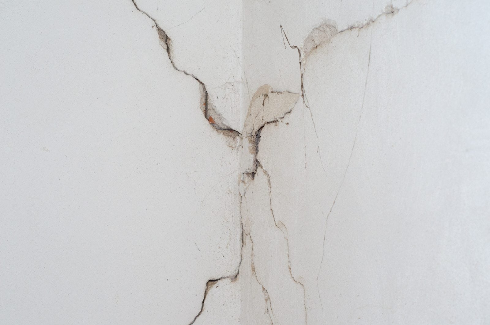 Multiple cracks meeting in a white interior wall corner