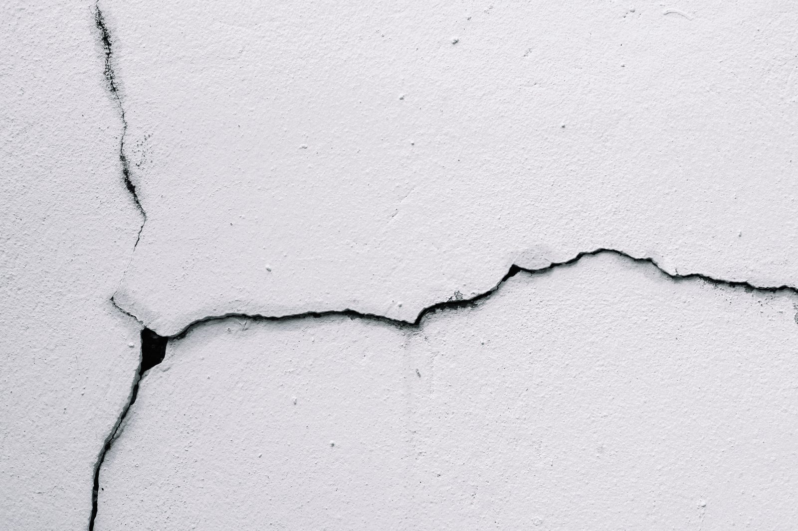 Branching crack spreading across a white painted wall